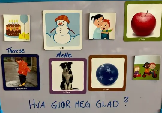 Bilde av en tavle hvor barn har satt opp bilder av ting som gjør dem glad.