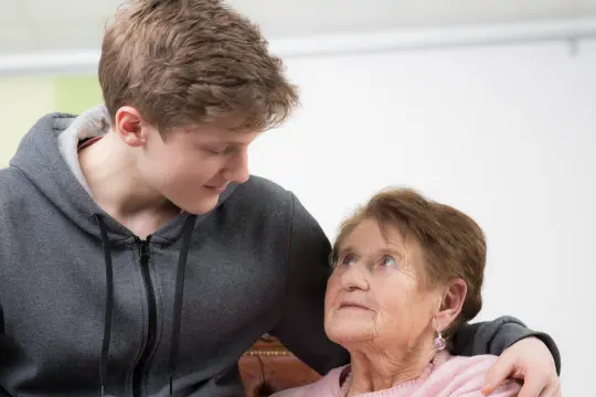 En gutt som sitter sammen med ei eldre dame. En gutt som sitter sammen med ei eldre dame.