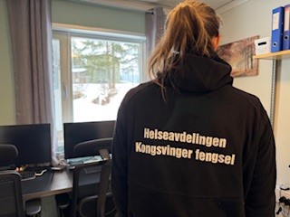 Bilde av en ansatt med genser som det står Helseavdelingen Kongsvinger fengsel på.