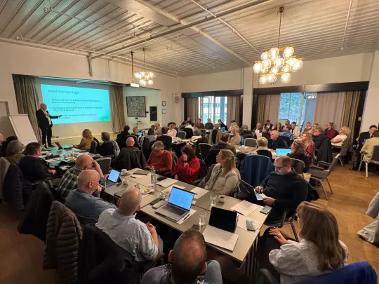 Bilde av konferansesalen på vinger hotell hvor de folkevalgte og administrasjonen sitter og hører på kommunedirektøren.