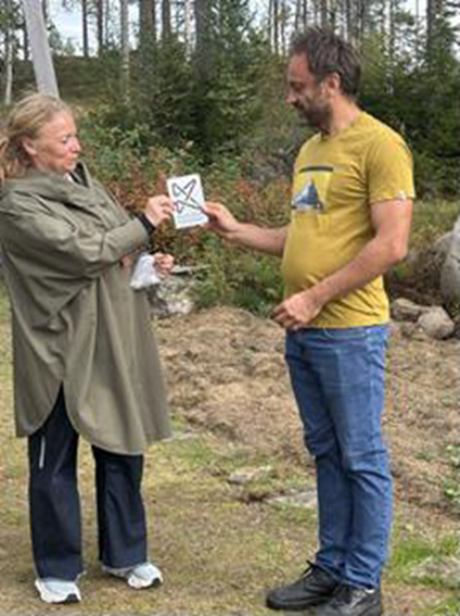 Eieren av Oppistua i Possåsen, Marcin Szczesniak får en plakett av styreleder i Kulturminnefondet, Hanne Kristin Jakhelln for istandsettingen av sommerfjøset. Slike tiltak er viktige for å synliggjøre eierens innsats.