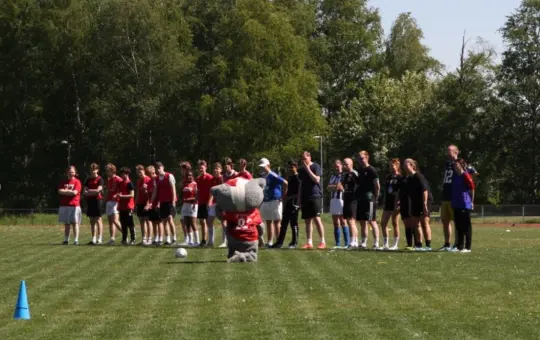 Fotballspillere som står oppstilt på fotballbanen før kamp.