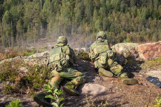 Heimvernet som ligger i skogen på øvelse. Ser to personer som ligger med våpen.