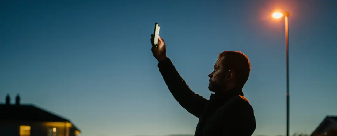 Bilde av en person som holder mobilen opp i lufta for å lete etter mibildekning.