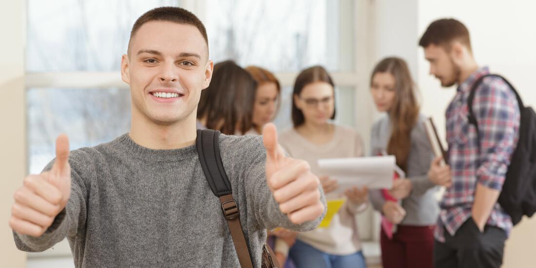 Bilde av seks ungdommer. En mannlig student i forkant som viser glede med å holde begge tomler opp. Bilde av seks ungdommer. En mannlig student i forkant som viser glede med å holde begge tomler opp.