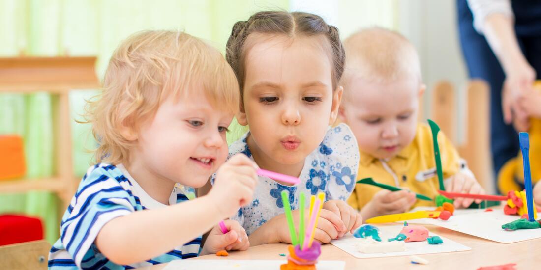 Barn som sitter ved et bord og leker i barnehagen. Det er fokus på to barn.