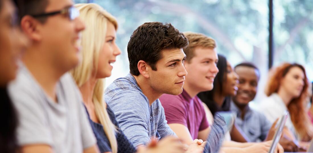 Studenter som sitter i en skolesituasjon og lytter interessert på undervisningen.