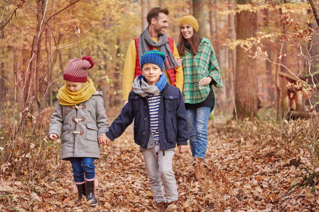 Familie på fire på tur i skogen en høstdag.