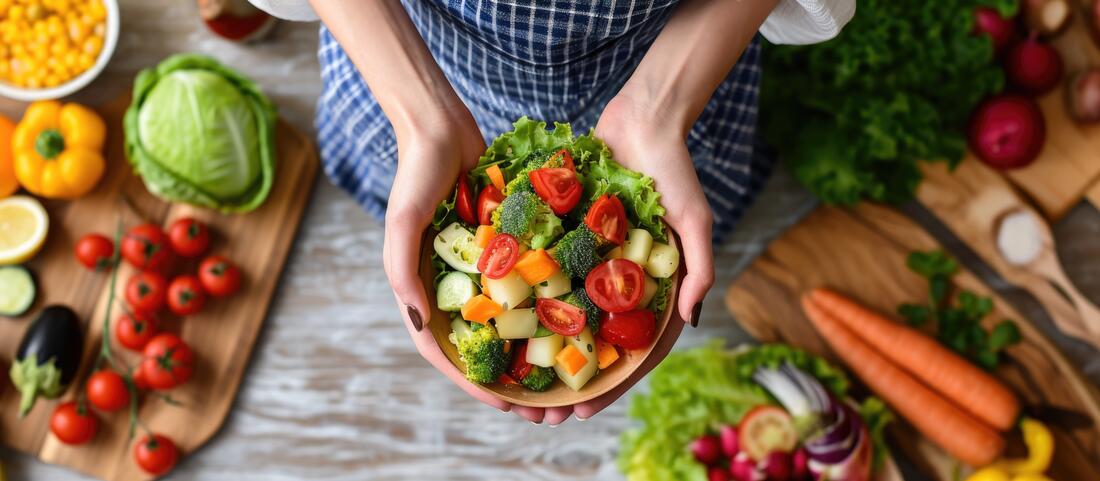 Bilde av ei dame som holder en skål med salat og sunne grønnsaker.