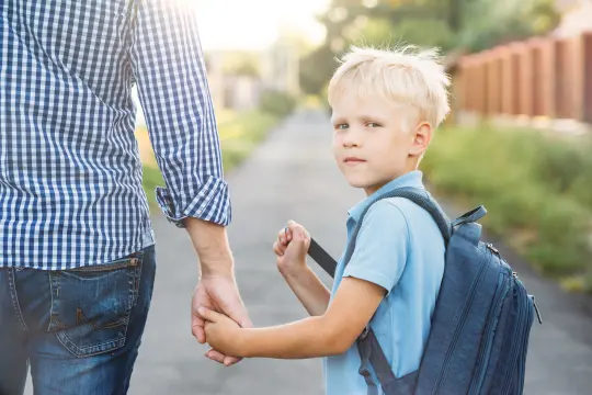 En gutt på veg til første skoledag sammen med pappaen sin.